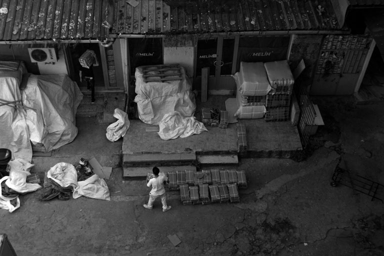 Black and white view of workers handling packages outside a warehouse in Istanbul, Türkiye.